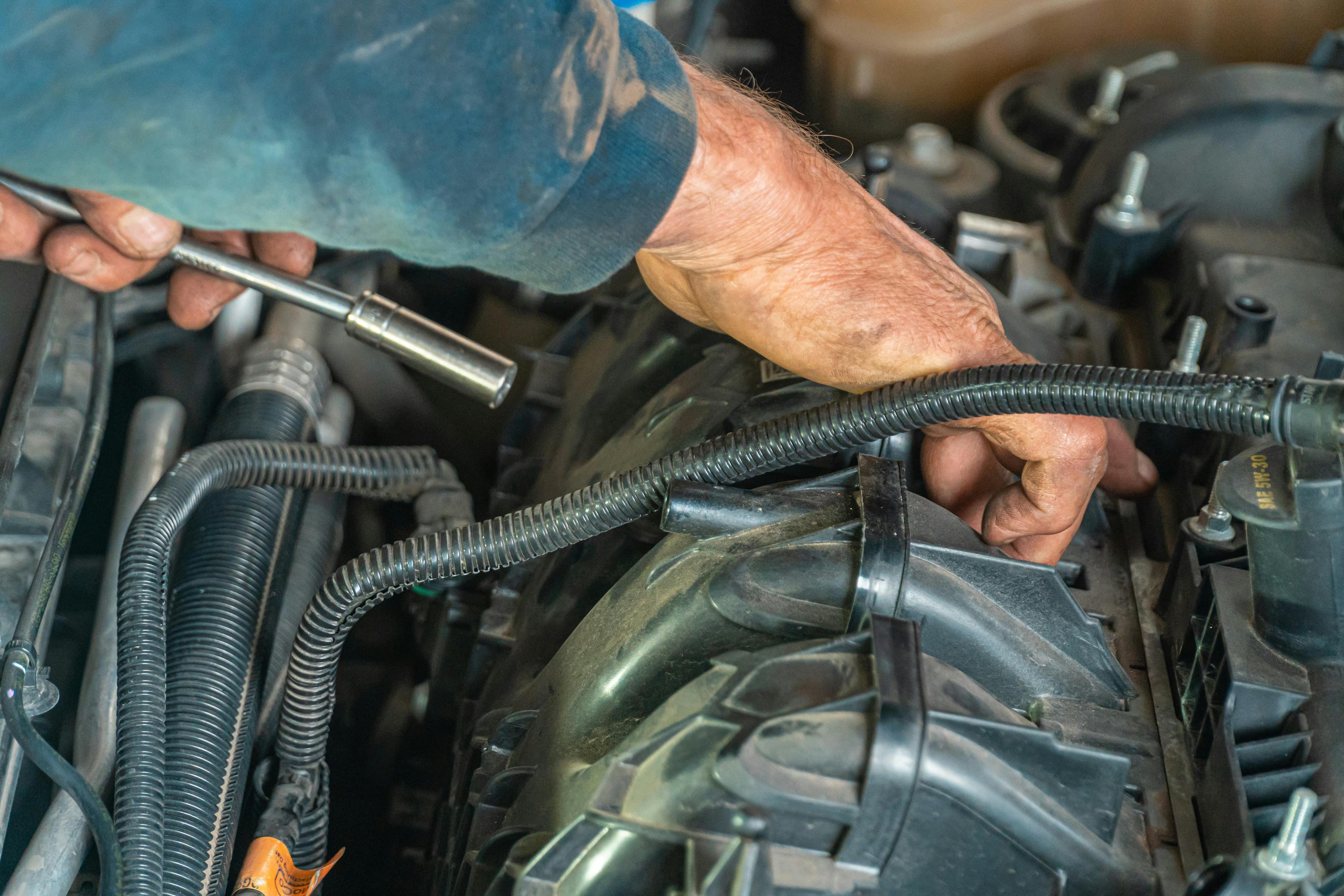 Hands holding an oil tool over an engine compartment